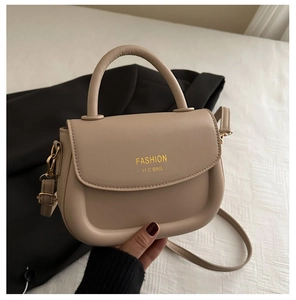 Detailansicht der beigen Satteltasche mit rundem U-Boden und goldenem Mode-Logo-Aufdruck