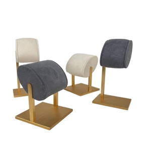 Detail of velvet watch display stands with gold metal bases in grey and beige