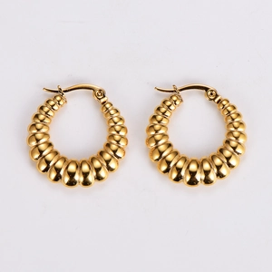 Macro detail of gold-plated stainless steel hoop earrings with textured ripple design