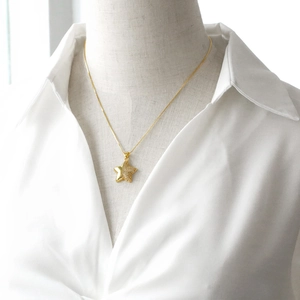 Gold star pendant necklace with zircons on a white collar model, minimalist style