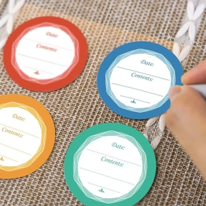 Waterproof date and content labels for glass jars in four colors on a woven surface