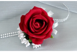 Macro detail of red velvet rose boutonniere with silver sequin ribbon and white berries