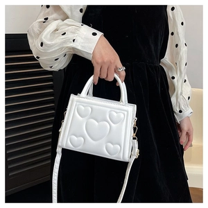 Détail du sac à main blanc gaufré de cœurs avec bandoulière porté par un mannequin