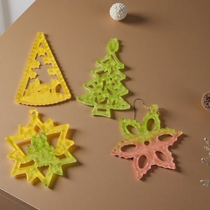 Detailed view of laser-cut acrylic Christmas tree and snowflake charms with golden hooks