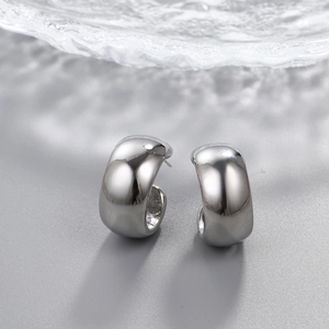 Macro shot of silver C-shaped teardrop earrings with a polished mirror finish on gray