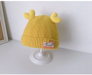 Detailed macro view of yellow knit baby hat with cute heart accents and soft textures