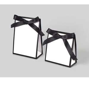 Détail de sacs cadeaux blancs avec bordure noire et nœuds en satin pour bijoux