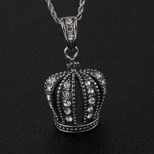 Macro shot of a silver crown pendant with clear rhinestones on black leather background