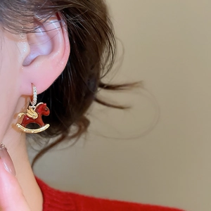 Vue macro de boucles d'oreilles cheval en émail rouge et zircons sur un mannequin