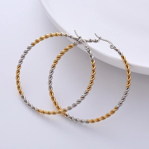Detalle de aretes de aro bicolores oro y plata de 50 mm con diseño de cuerda torcida