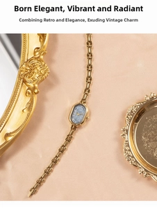 Macro detail of oval gold-tone bracelet watch with dark blue dial and vintage metal chain