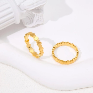 Polished gold wavy stacked rings with beaded circle design on white aesthetic backdrop