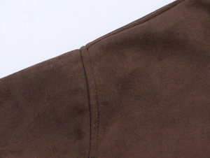 Detail view of dark brown suede fabric texture and high-quality stitching on the jacket