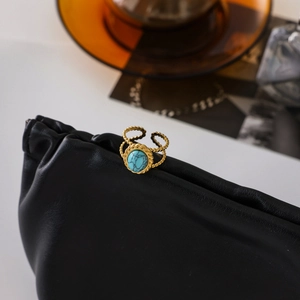 Detail of 18K gold plated stainless steel ring with turquoise stone on leather background