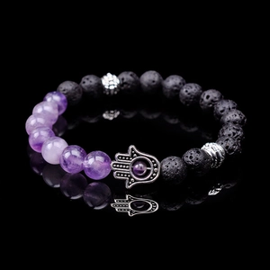Macro shot of Hamsa hand charm and purple amethyst with black lava stone beads