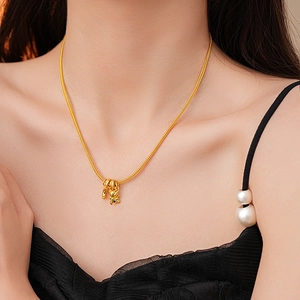 Detailed close-up of a gold bear and moon pendant on a sleek snake chain necklace