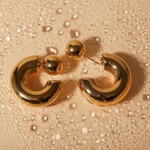 Macro shot of 16k gold plated C-shaped chunky earrings with water droplet aesthetic background