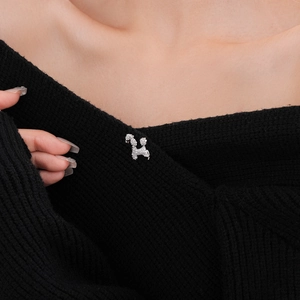 Detailed view of a silver puppy brooch with white zircons pinned on black knitwear