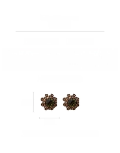 Macro shot of French vintage flower stud earrings with green center stone and rhinestones