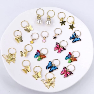 Close-up of golden hair rings with colorful enamel butterflies, stars and pearl charms