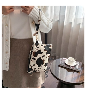 Detail view of cow print envelope clutch with gold hardware shown with lifestyle decor