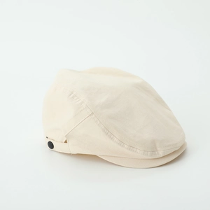 Detail of cream flat cap showing cotton-linen texture and black side button accent