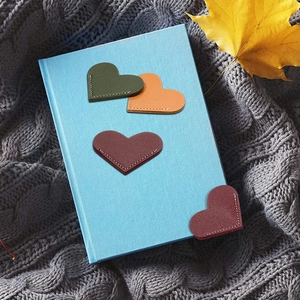 Set of four heart-shaped leather bookmarks in autumn colors on a blue notebook