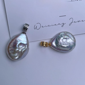 Macro shot of baroque pearl pendants with iridescent luster and engraved metal clasps