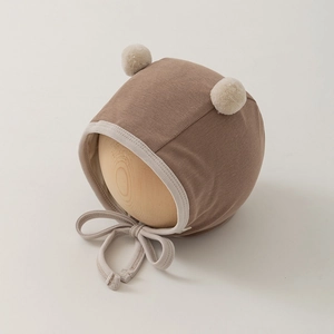 Detail of ribbed knit baby bonnet with cute pom poms and secure chin ties