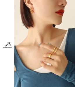 Detailed view of gold stainless steel twisted earrings and rings set on a model