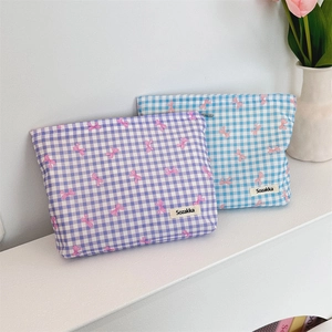 Floral makeup bags with purple and blue grid patterns and pink bows on a shelf