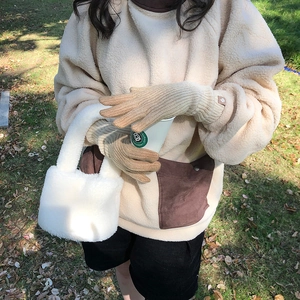 Detail of warm beige knitted gloves and plush handbag in an outdoor autumn setting