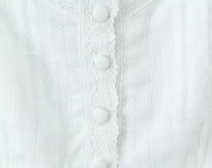 Détail du tissu en coton lin blanc avec dentelle festonnée et boutons en tissu