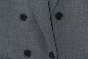 Détails des boutons noirs à double boutonnage sur le blazer gris en tissu tissé de qualité