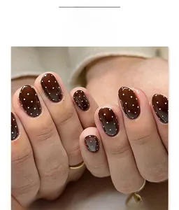 Detailed view of short round press-on nails in coffee brown with white polka dot pattern