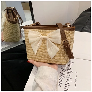 Close-up of woven straw bucket bag with elegant chiffon bow and brown leather trim