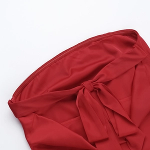 Detailed view of red satin fabric featuring a decorative bow tie design and fine stitching