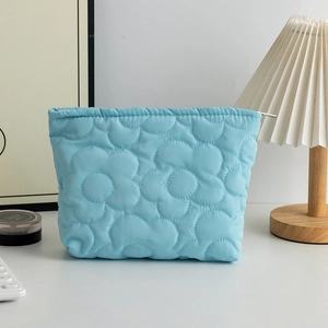 Dettaglio della borsa trucco azzurra trapuntata con motivi floreali e zip in argento