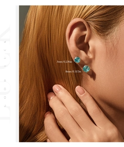 Detail view of 7mm and 8mm light blue round stud earrings worn on a model ear