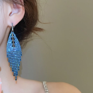 Close-up of model wearing blue rhinestone triangle tassel drop earrings with long fringe