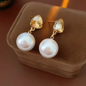 Champagne pear-cut crystal and round pearl earrings on velvet box, vintage luxury style