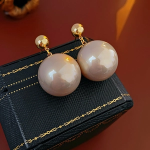 Macro shot of large champagne pearl earrings on a black leather jewelry box