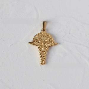 Macro shot of 18K gold plated Caduceus medical pendant with MEDICO engraving