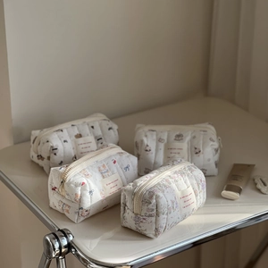 Detailed macro of four quilted cotton pouches featuring floral and animal patterns