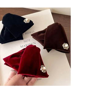 Detail of velvet flower hair clips in black, brown and red with pearl center ornaments