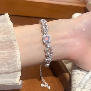 Gros plan d'un bracelet en perles à deux rangs avec pierre violette au poignet féminin
