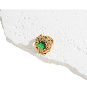Golden ring with emerald green stone and colorful zircon accents on white stone