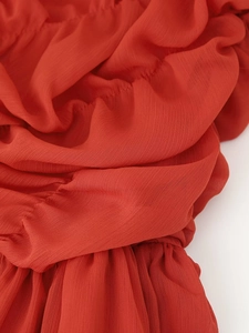 Detailed close-up of red pleated chiffon fabric texture with delicate vertical draping