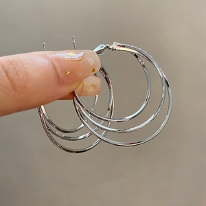 Detail view of silver triple-hoop earrings featuring frosted texture and polished finish
