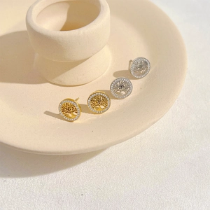 Gold and silver tree of life earrings with rhinestone accents on ceramic tray
